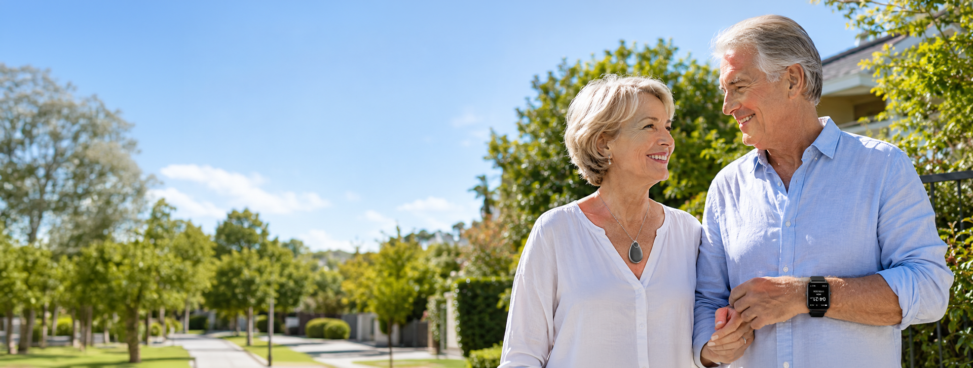 Happy senior Australian couple walking outside wearing VitalALERT™ medical alert pendant and 4G GPS smartwatch