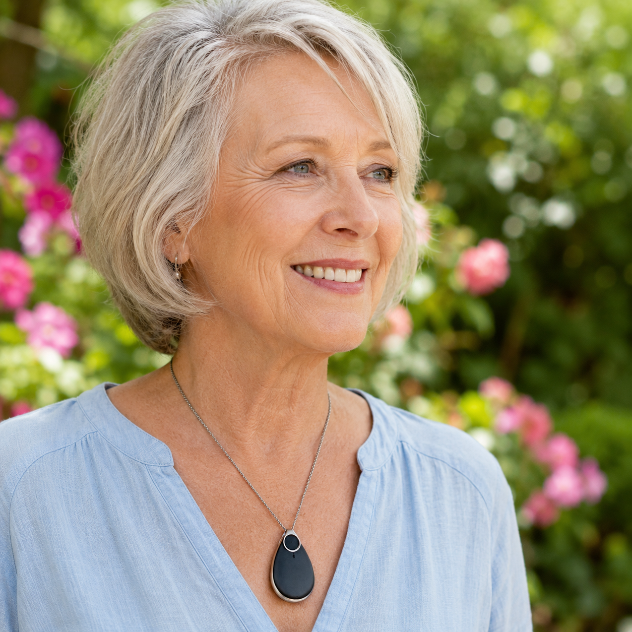 Senior woman smiling in the garden wearing the VitalALERT™ pendant
